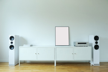 Poster Frame Mockup in white modern interior. Modern audio stereo system with white speakers on...