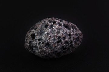 Black porous basalt stone on a black background