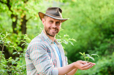 happy earth day. Eco living. farming and agriculture cultivation. Gardening. muscular ranch man in cowboy hat care plants. successful farmer hold plant in ground in hands. Eco farm worker. Earth day