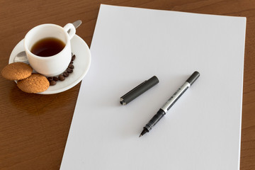 Closeup of wood desktop with blank sheet of paper, pen, and other items