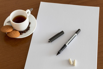 Closeup of wood desktop with blank sheet of paper, pen, and other items