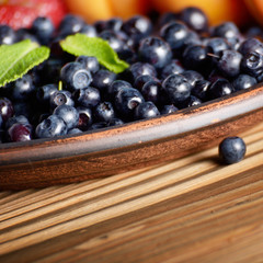 Clay plate full of Ripe organic blueberries on wooden table