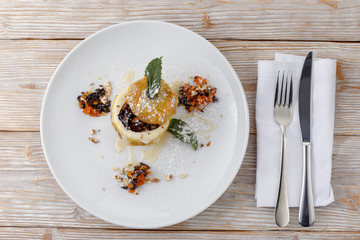 baked apple on a plate with dried fruits, honey, walnuts, powdered sugar, top view