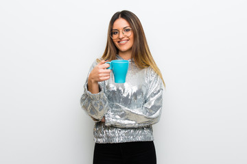 Young woman with glasses over white wall holding a hot cup of coffee
