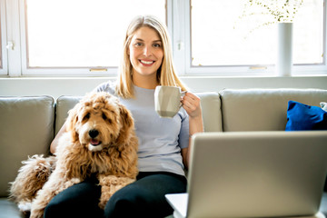 woman with his Golden Labradoodle dog at home drinking coffee