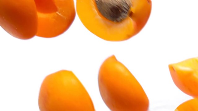 Halves ripe apricots fly close-up on white background in slow motion