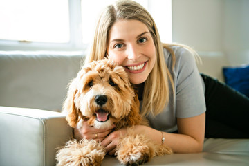 woman with his Golden Labradoodle dog at home