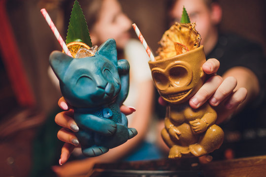 Tiki Drink Cocktails. Tropical tiki cocktails man and woman are holding.