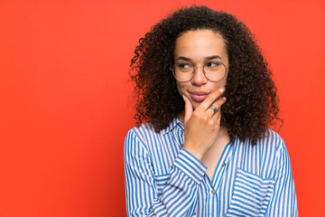 Dominican woman over red wall thinking an idea