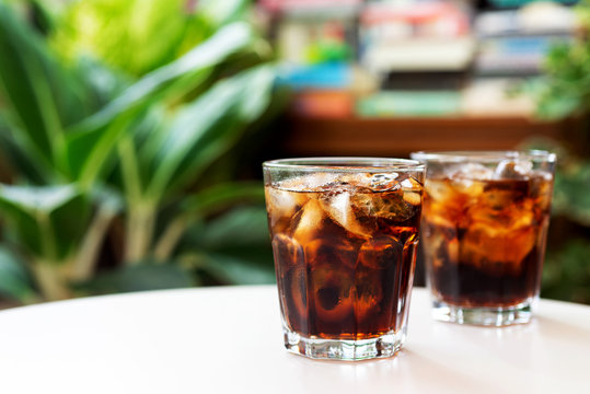 a glass of cola with iced on white table