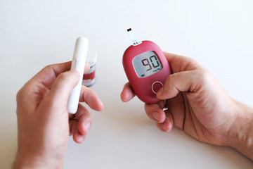 Man sick on diabetes, is checking his glucose level by glucometer.