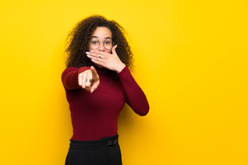 Dominican woman with turtleneck sweater pointing with finger at someone and laughing
