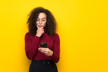 Dominican woman with turtleneck sweater with a mobile and thinking