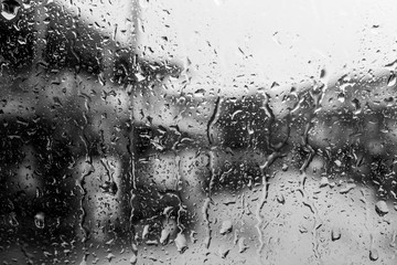 Rain drops on window in black and white abstract background.