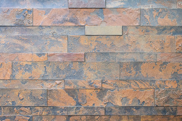 Natural stone, smooth linear brickwork, rusty relief texture. The wall is made of stone, the surface is textured, red, rusty color.