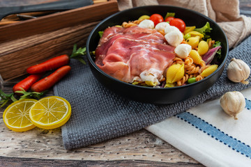 Salad made with cooked pasta, mixed green salads, cherry tomatoes, Mozzarella cheese and smoked ham served with accompaniment