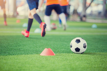 football between marker cones on green artificial turf with blurry soccer team training