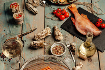  A glass of white wine, oysters and fresh-frozen fish. View from above.