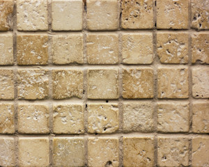 wall of small ceramic tiles texture under natural stone sand-colored retro