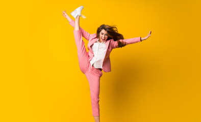 Young woman jumping over isolated yellow wall