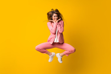 Young woman jumping over isolated yellow wall