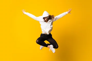 Deurstickers Young woman jumping over isolated yellow wall © luismolinero