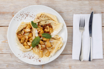 Pancakes with apple and raisins on a plate flat lay