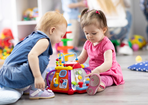 children toddlers girls play together educational toys in playroom