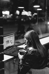 Businesswoman, girl working on laptop in cafe, smartphone, pen, use computer. Freelancer works remotely. Online marketing, education for adulte. Night city, dark theme. black and white