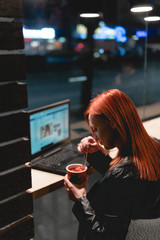 Businesswoman, girl working on laptop in cafe, smartphone, pen, use computer. Freelancer works remotely. Online marketing, education for adulte. Night city, dark theme.