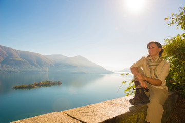 Fototapeta premium Woman Relax and Enjoy the Panoramic View Over Alpine Lake Maggiore with Brissago Islands and Mountain with Sunshine in Ticino, Switzerland.