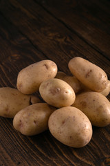 Heap of fresh clean potatoes on rustic wooden surface. Organic food, carbs, tubers.