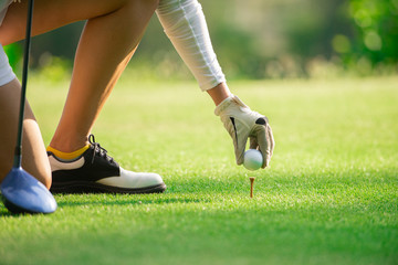 Close up on woman golfer hand putting golf ball on tee at golf course ,Healthy Holiday Concept