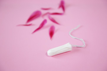 Clean white cotton tampon with red peony petals on pink background. Menstruation. Feminine Hygiene in periods, beauty treatment.