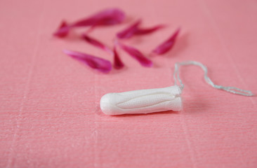 Clean white cotton tampon with red peony petals on pink background. Menstruation. Feminine Hygiene in periods, beauty treatment.