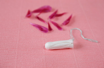 Clean white cotton tampon with red peony petals on pink background. Copy space. Menstruation. Feminine Hygiene in periods, beauty treatment.