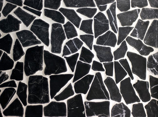 mosaic on the wall of uneven pieces of broken black stone