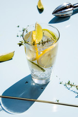 Lemonade or mojito cocktail with lemon and lime, cold refreshing drink or beverage with ice on a light blue backround. Retro style with artistic trendy shadows.