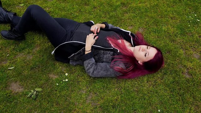 emo girl with purple hair pondering about life on the floor wide shot