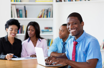Happy african american businessman with team and computer