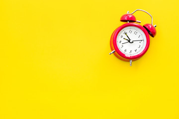 Red vintage alarm clock on a yellow background, top view