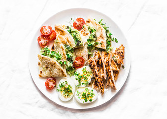 Grilled chicken, avocado cream cheese quesadilla, boiled eggs, vegetables - delicious snack, appetizer, tapas on a light background, top view