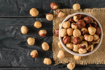 Scattered on the table roasted hazelnuts on a black wooden table. Prepared with the harvest of...