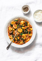 Potato turmeric gnocchi with bolognese sauce and spinach on a light background, top view
