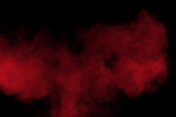 Red color powder explosion on black background. Freeze motion of red dust particles splash.