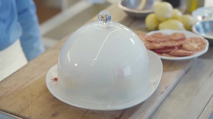 Close up amazing plate with big glass cover on top, inside dish is dry ice. Molecular kitchen. Body of chef in restaurant stand near table kitchen