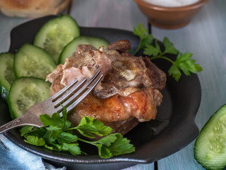 Juicy turkey steak and cucumber slices on a black ceramic plate