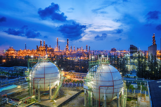Gas storage sphere tanks and pipeline in oil and gas refinery industrial plant with glitter lighting industry estate at twilight