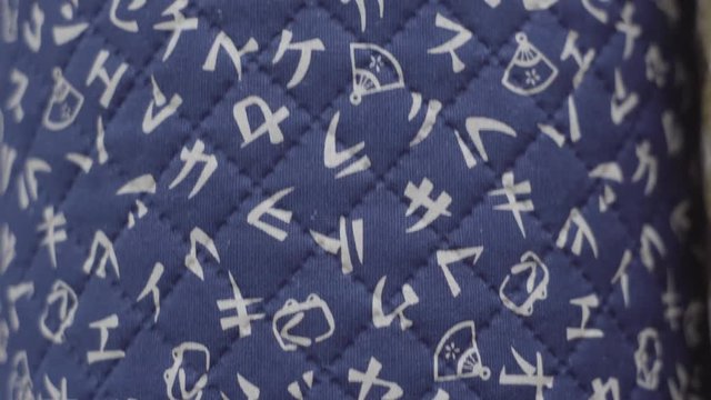 Punning upward, close up on blue quilted fabric with Kanji style, Japanese design printed onto surface.