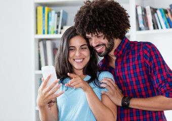 Laughing hipster love couple looking at mobile phone